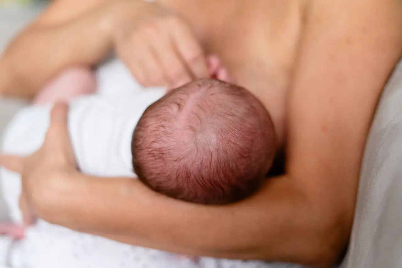 Tender moment of a mother breastfeeding her newborn, highlighting love and bonding.